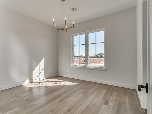 empty room featuring light hardwood / wood-style floors and a chandelier