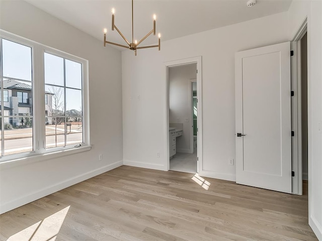 spare room featuring light hardwood / wood-style floors and a chandelier