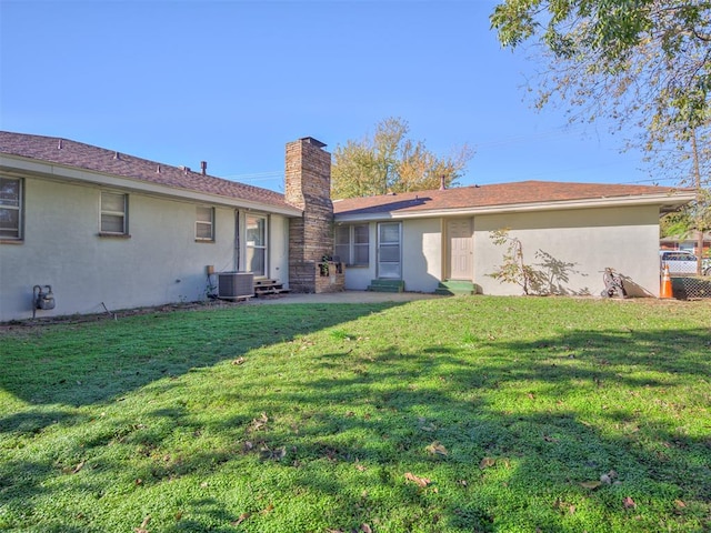 rear view of property featuring central air condition unit and a lawn