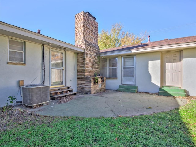 view of exterior entry featuring central air condition unit and a patio area