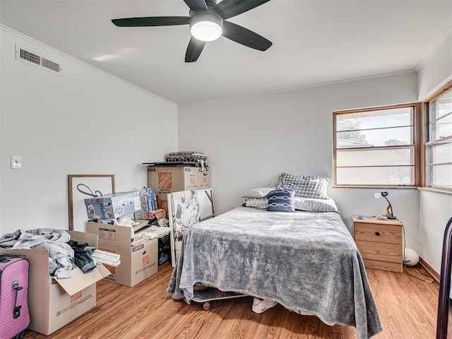 bedroom featuring ceiling fan, ornamental molding, and light wood-type flooring