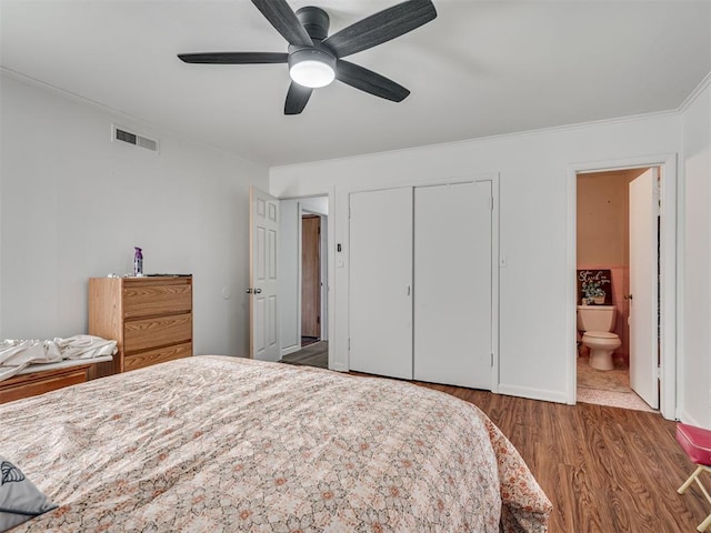 bedroom with dark hardwood / wood-style flooring, ensuite bathroom, ornamental molding, ceiling fan, and a closet