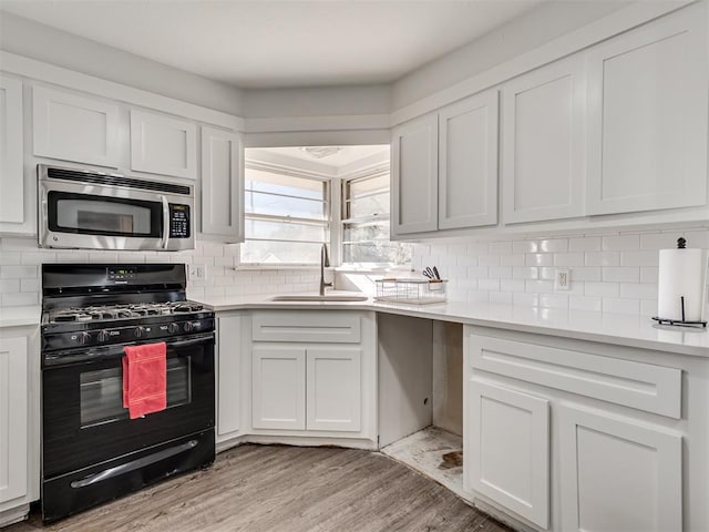 kitchen featuring gas stove, light hardwood / wood-style floors, sink, and white cabinetry