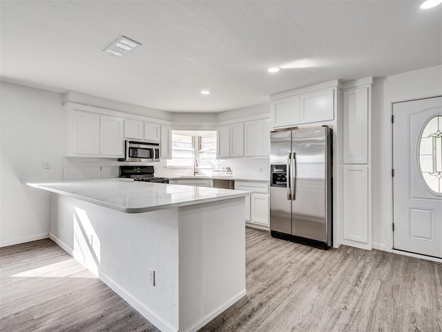 kitchen with white cabinets, appliances with stainless steel finishes, light hardwood / wood-style flooring, and plenty of natural light