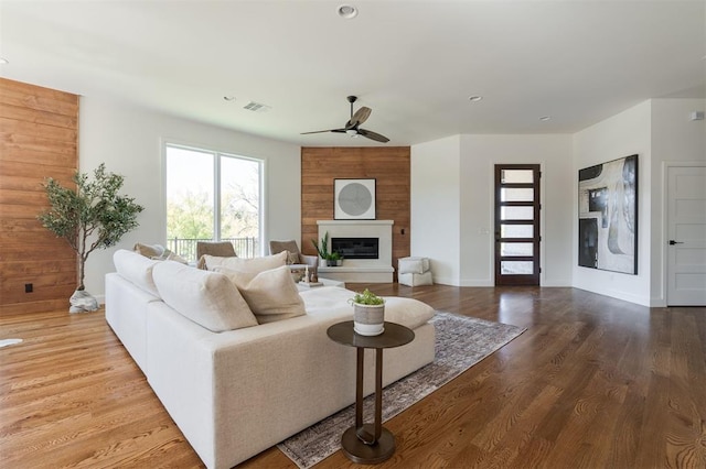 living room with ceiling fan, a fireplace, and hardwood / wood-style flooring