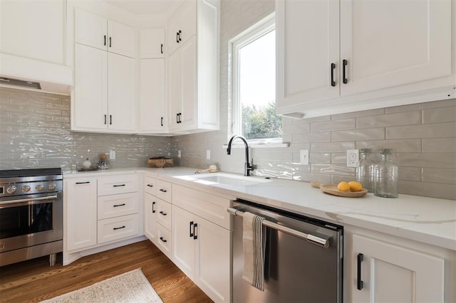 kitchen featuring backsplash, sink, dark hardwood / wood-style floors, appliances with stainless steel finishes, and white cabinetry