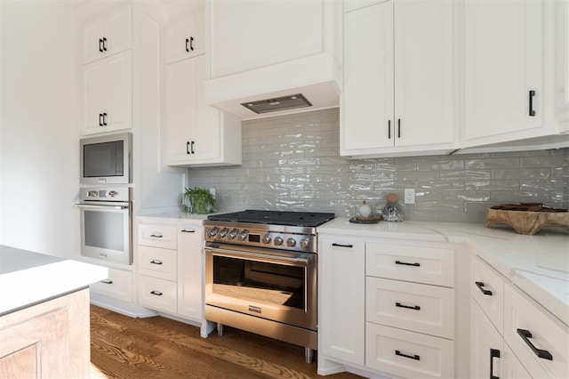 kitchen with dark hardwood / wood-style flooring, tasteful backsplash, light stone counters, stainless steel appliances, and white cabinets