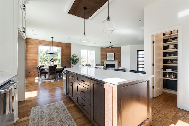 kitchen featuring light stone countertops, hanging light fixtures, dark wood-type flooring, and wood walls