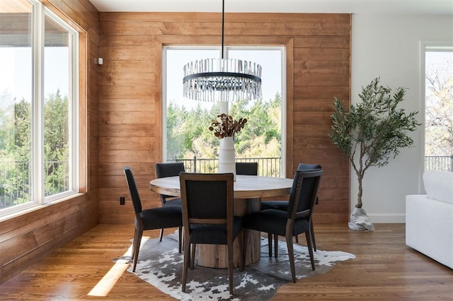 dining area featuring a wealth of natural light, wood walls, hardwood / wood-style flooring, and an inviting chandelier