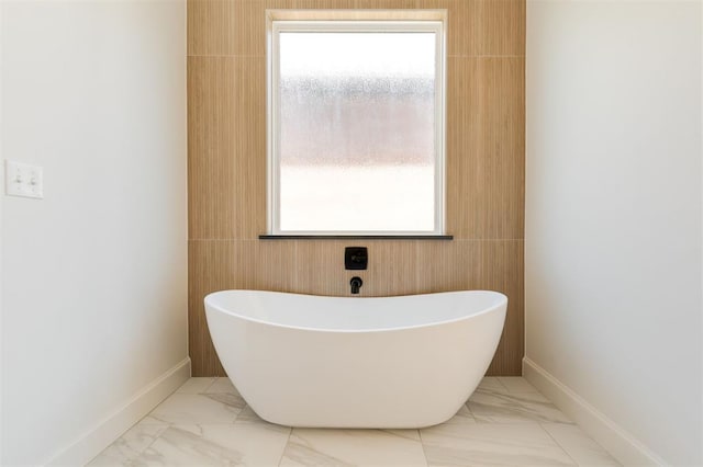 bathroom featuring a wealth of natural light, a tub, and tile walls