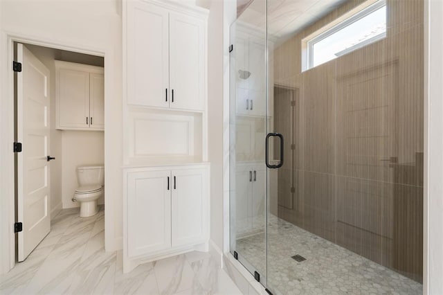 bathroom featuring a shower with door and toilet