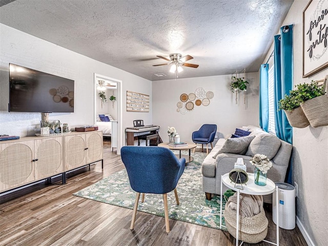 living room with hardwood / wood-style floors, ceiling fan, and a textured ceiling