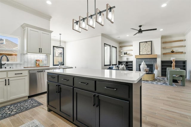 kitchen featuring light hardwood / wood-style flooring, white cabinetry, hanging light fixtures, and stainless steel dishwasher