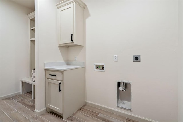 laundry room with hookup for an electric dryer, washer hookup, light wood-type flooring, and cabinets