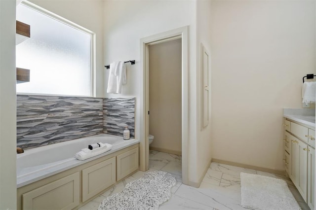 bathroom with a washtub, vanity, and toilet