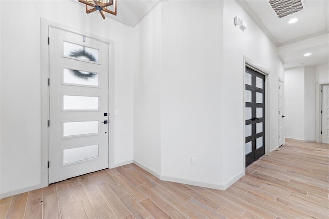 foyer featuring crown molding, baseboards, visible vents, and light wood-style floors