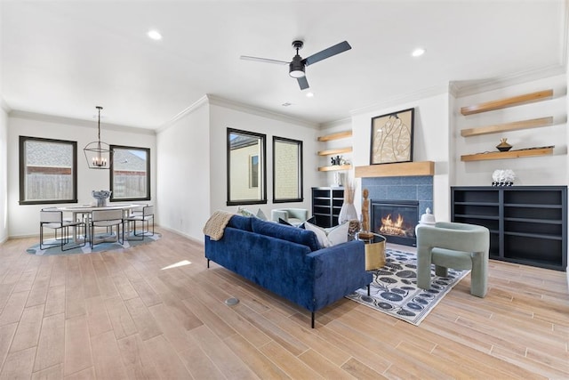 living area featuring light wood finished floors, crown molding, and a tile fireplace