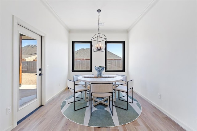 dining area featuring baseboards, light wood-style flooring, a chandelier, and crown molding