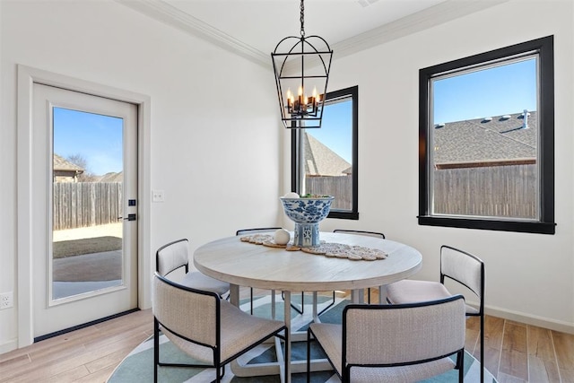 dining space with crown molding, light wood-style flooring, and a healthy amount of sunlight