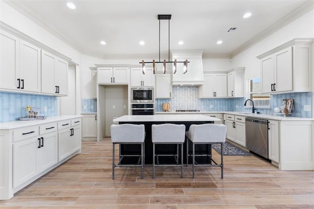 kitchen with stainless steel appliances, a kitchen island, white cabinetry, light countertops, and pendant lighting