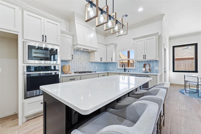 kitchen with appliances with stainless steel finishes, white cabinets, light countertops, and hanging light fixtures