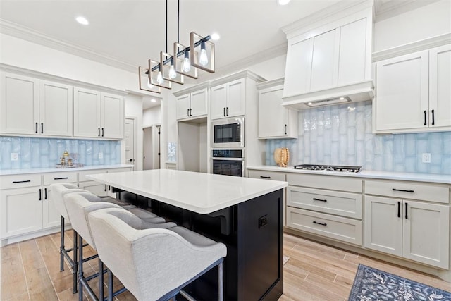 kitchen with decorative light fixtures, stainless steel appliances, light countertops, ornamental molding, and white cabinets