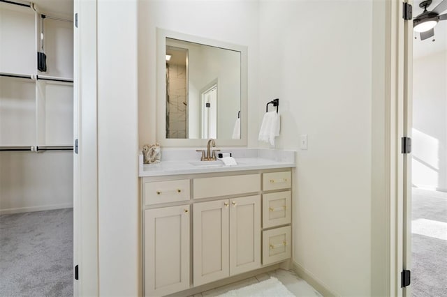 bathroom featuring baseboards, a spacious closet, and vanity