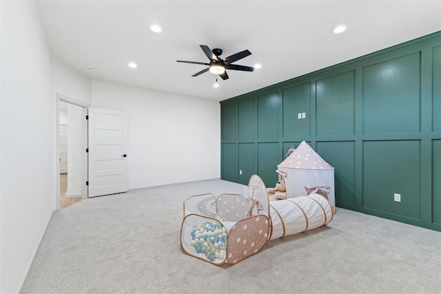 sitting room with light carpet, recessed lighting, a ceiling fan, and a decorative wall