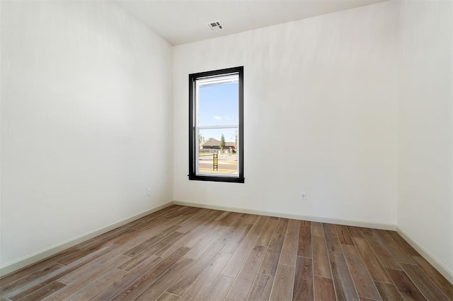 unfurnished room featuring visible vents, baseboards, and wood finished floors