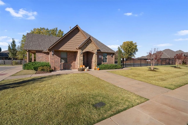 view of front of property featuring brick siding, a front lawn, a shingled roof, and fence