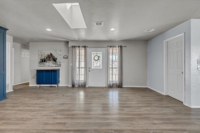 entrance foyer with wood-type flooring, a textured ceiling, and a skylight