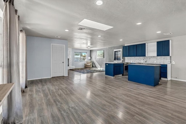 kitchen featuring dark hardwood / wood-style flooring, a skylight, tasteful backsplash, blue cabinetry, and a kitchen island