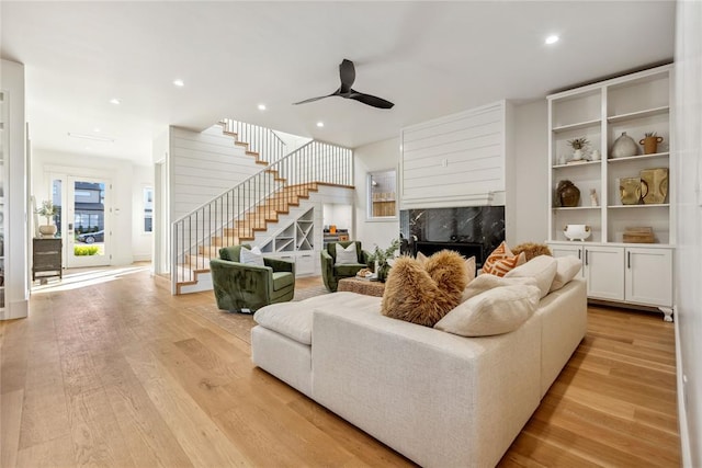 living room featuring a premium fireplace, ceiling fan, and light hardwood / wood-style floors