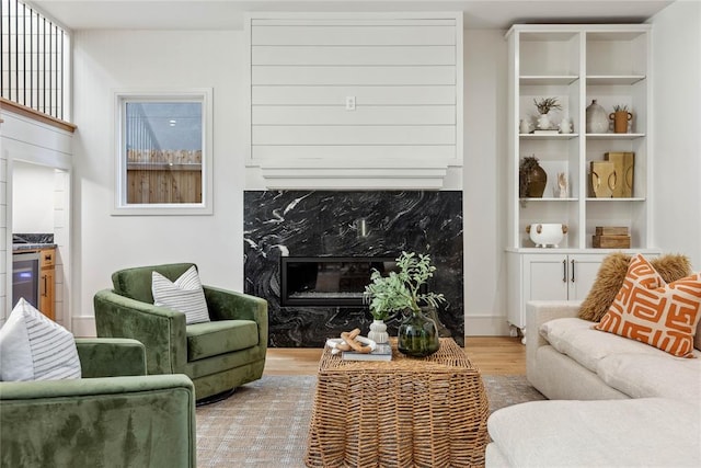 living room featuring a premium fireplace, beverage cooler, and light hardwood / wood-style flooring