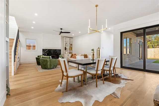 dining area with ceiling fan with notable chandelier and light hardwood / wood-style floors