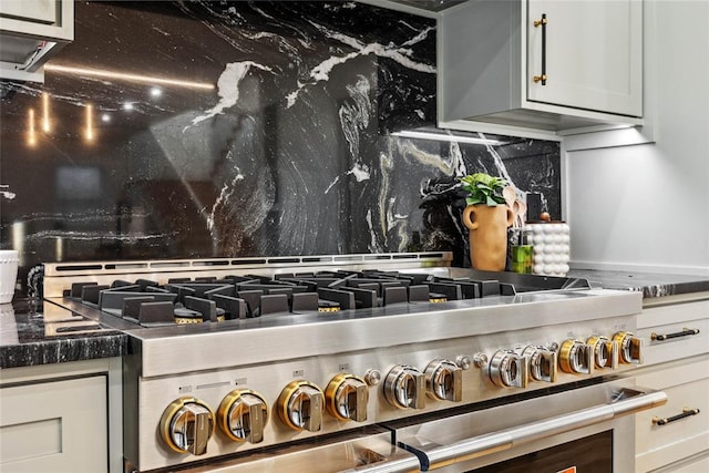 details featuring tasteful backsplash, white cabinetry, and high end stainless steel range