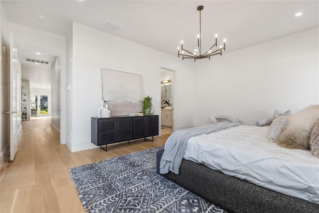 bedroom with wood-type flooring, connected bathroom, and a chandelier