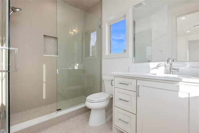 bathroom featuring a tile shower, vanity, and toilet