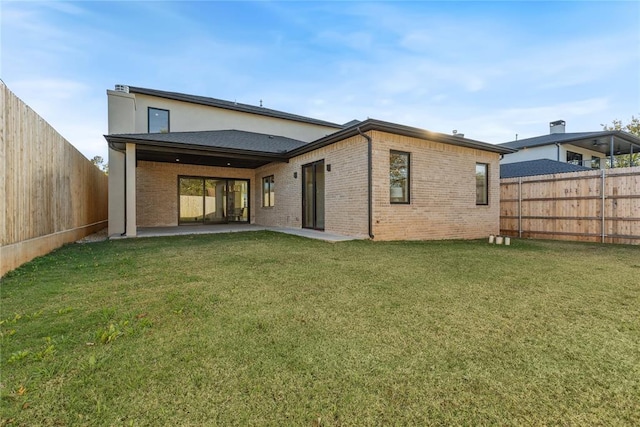 back of property with a patio area and a yard