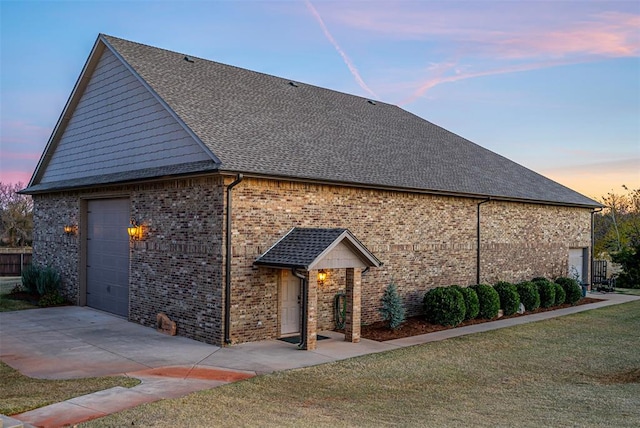 property exterior at dusk featuring a garage and a lawn