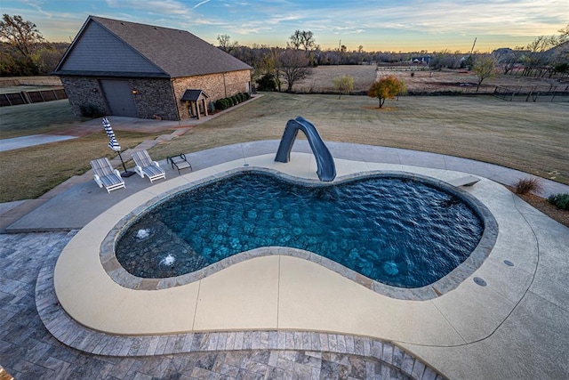 pool at dusk featuring a patio and a water slide