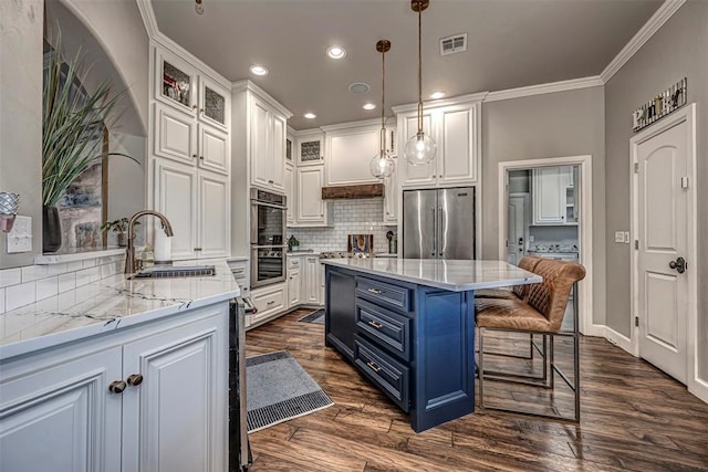 kitchen with blue cabinetry, white cabinetry, sink, stainless steel appliances, and decorative light fixtures