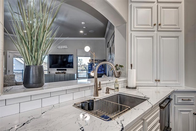 kitchen featuring plenty of natural light, crown molding, white cabinetry, and sink