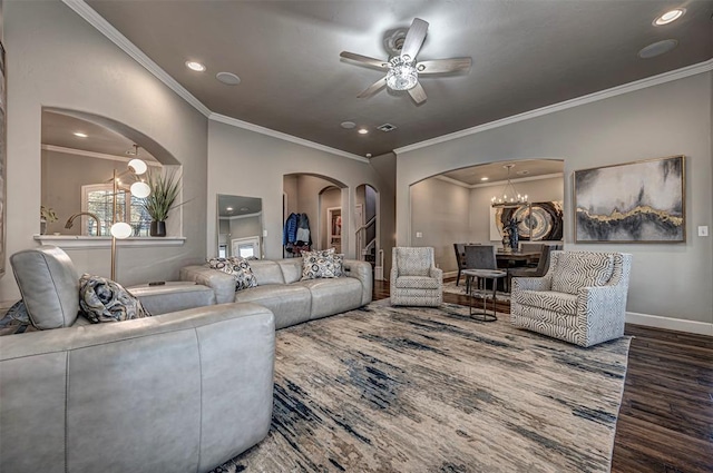 living room featuring dark wood-type flooring, ceiling fan with notable chandelier, and ornamental molding