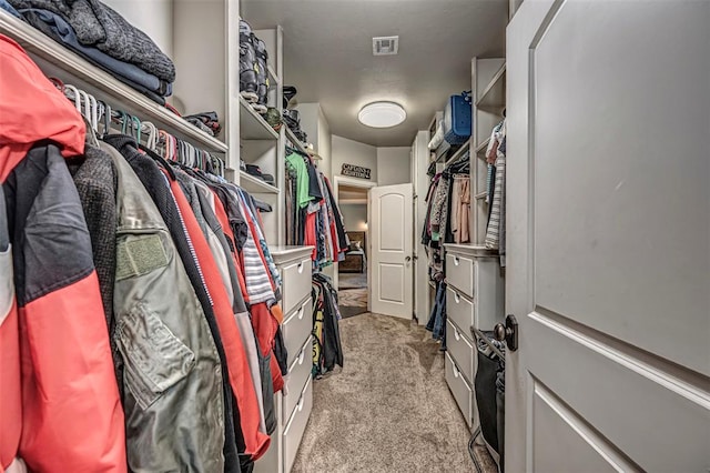 walk in closet with light colored carpet