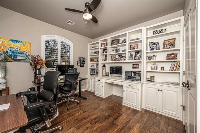 office space featuring ceiling fan, built in desk, and dark hardwood / wood-style floors