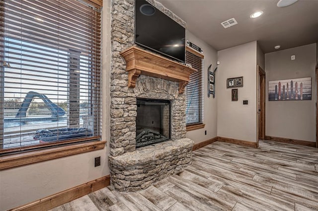 living room with a stone fireplace and light wood-type flooring