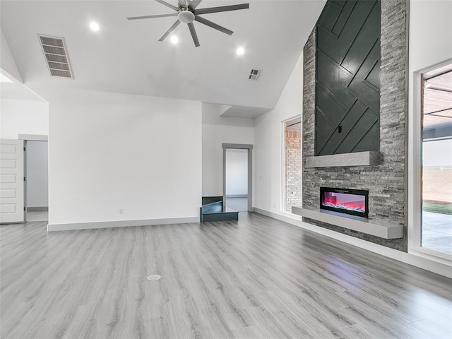 unfurnished living room featuring a stone fireplace, ceiling fan, high vaulted ceiling, and light wood-type flooring