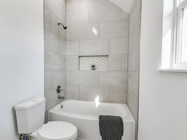 bathroom with tiled shower / bath combo and toilet