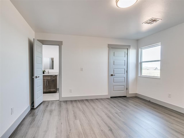 unfurnished bedroom with connected bathroom and light hardwood / wood-style flooring